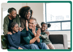 An image showing a family smiling and high fiving on the couch in their apartment.